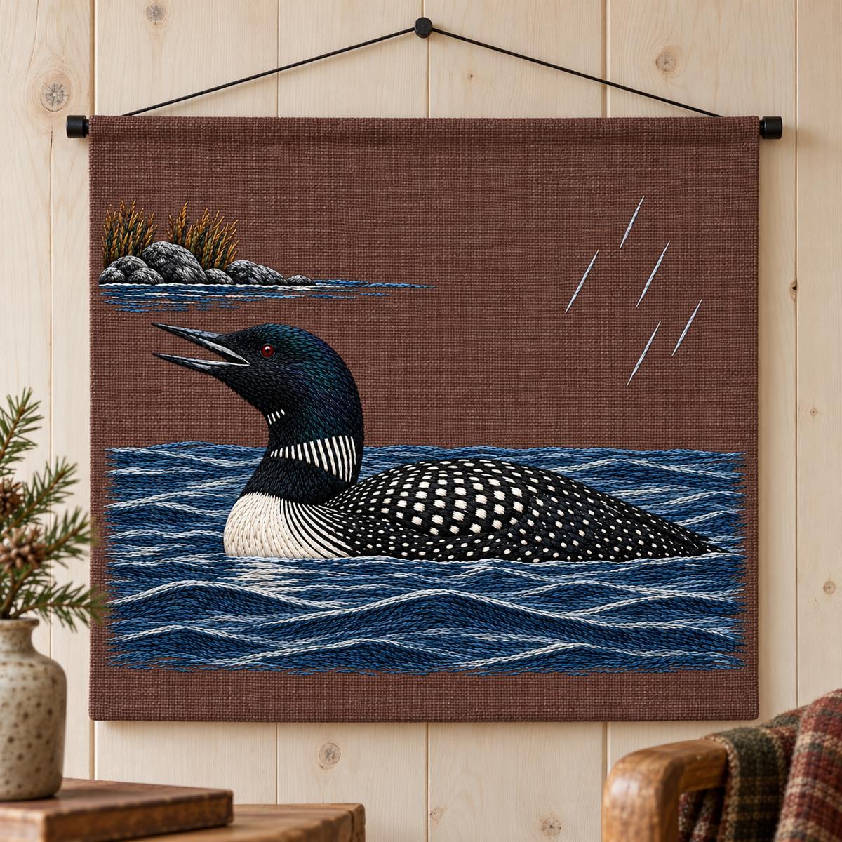 Loon embroidery design in a digital mockup of plum-brown linen wall-hung textile panel with small black rod at top and weighted straight lower hem, near-frontal on pale timber wall; rain scene fully visible. Placement inspiration for Study 35.