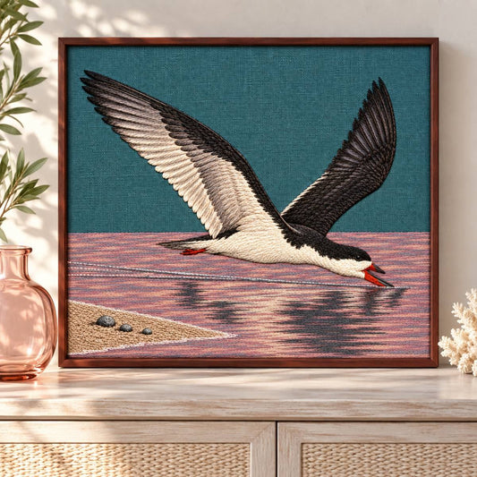 Skimmer embroidery design shown in a digital mockup of teal linen embroidery inset in a slim rosewood frame, front-on above a pale coastal console, one rose glass vessel beside frame. Study 37.