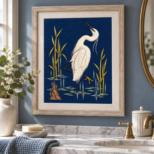 Egret embroidery design shown in a digital mockup of portrait egret embroidery framed in pale driftwood above a quiet blue-grey bathroom console. Study 39.