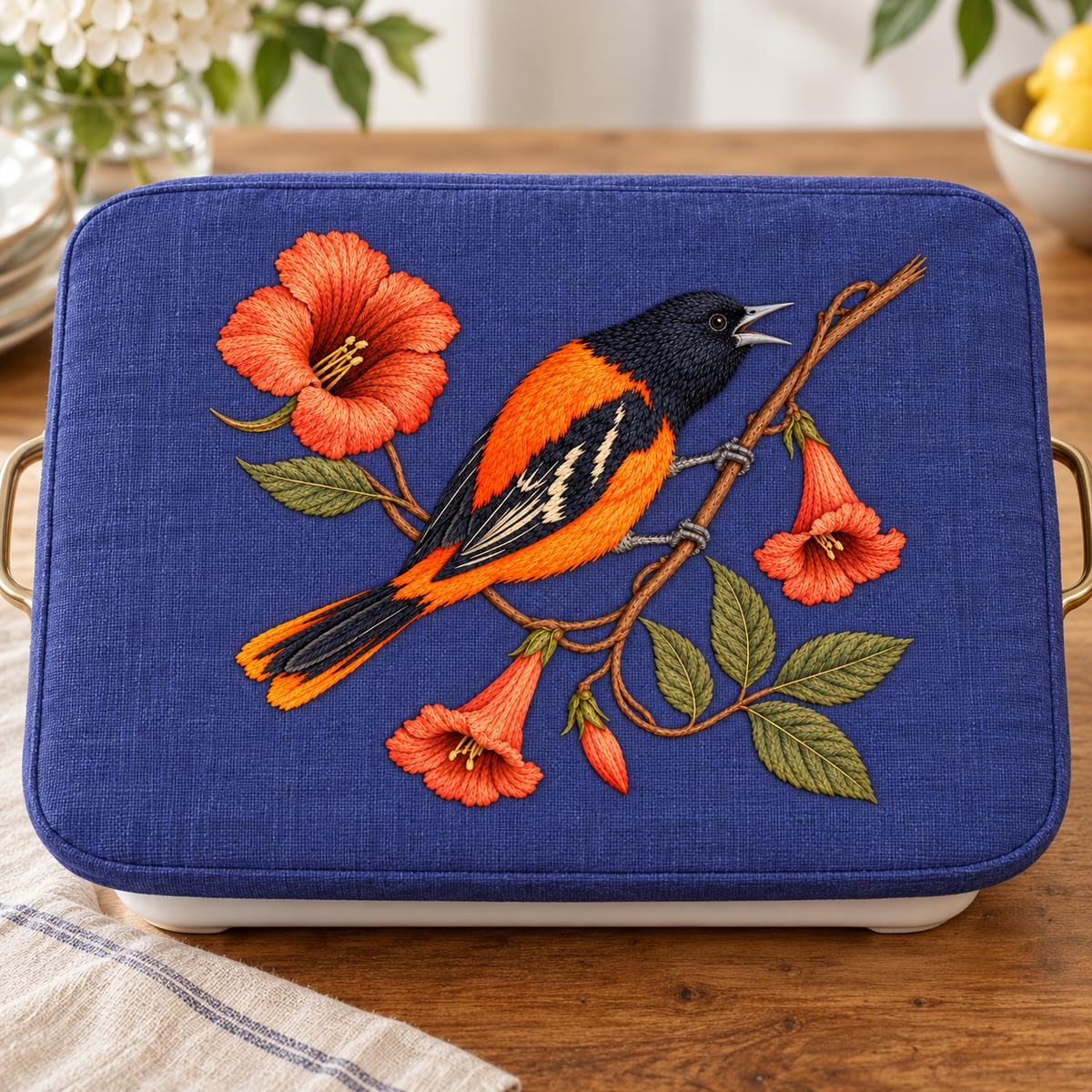 Oriole embroidery design in a digital mockup of blue-violet linen cover on rectangular serving warmer, straight-on. Placement inspiration for Study 60.