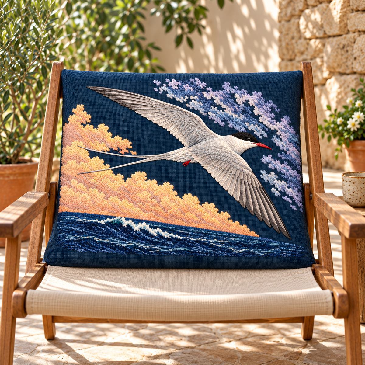 Arctic Tern embroidery design in a digital mockup of A horizontal embroidered panel in the back cushion of a vintage canvas deckchair on a shaded terrace, view nearly frontal, no design hidden by chair rails. Placement inspiration for Study 61.