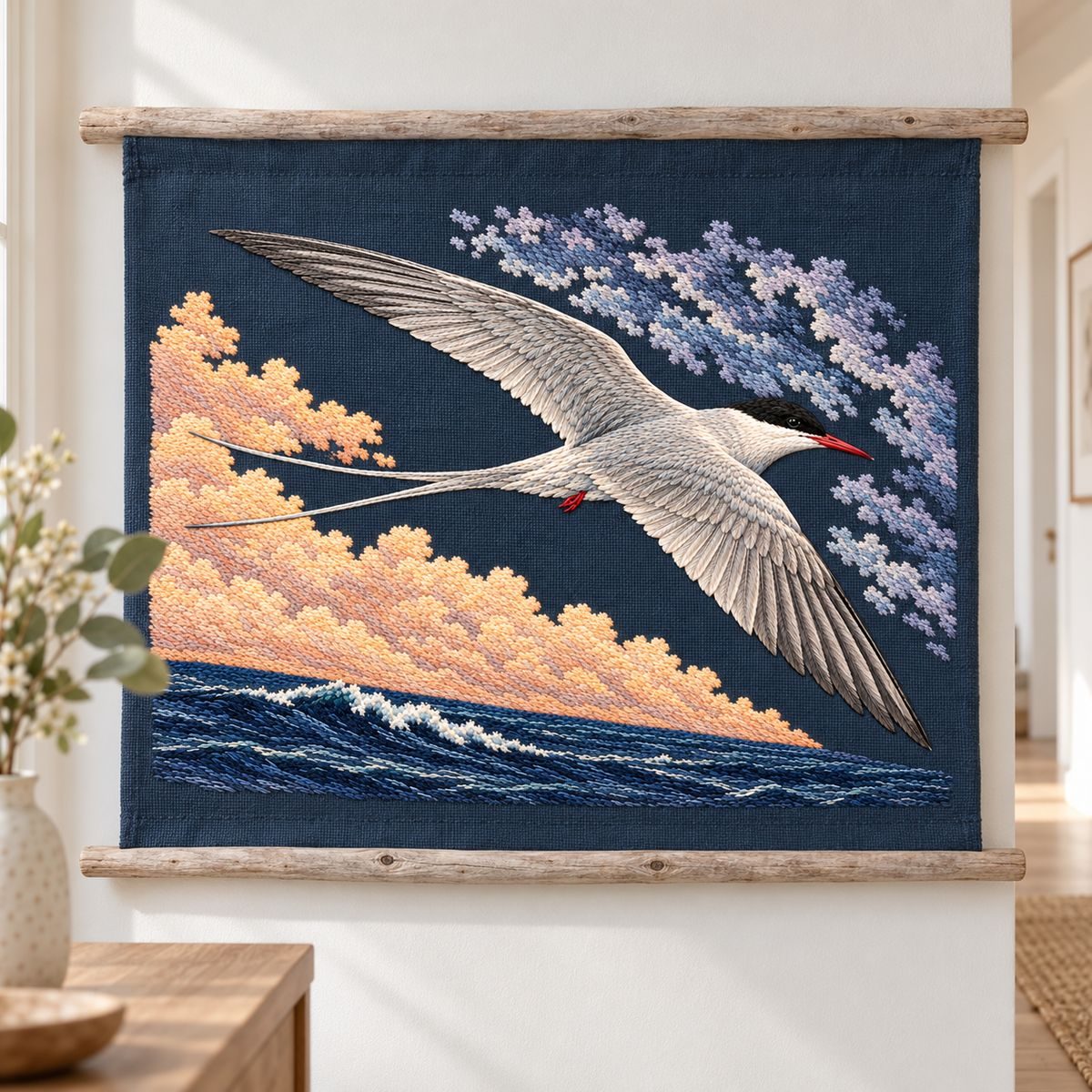 Arctic Tern embroidery design in a digital mockup of A petrol-plum linen wall hanging on two short horizontal bleached driftwood battens, mounted level in a calm white hallway; complete motif. Placement inspiration for Study 61.