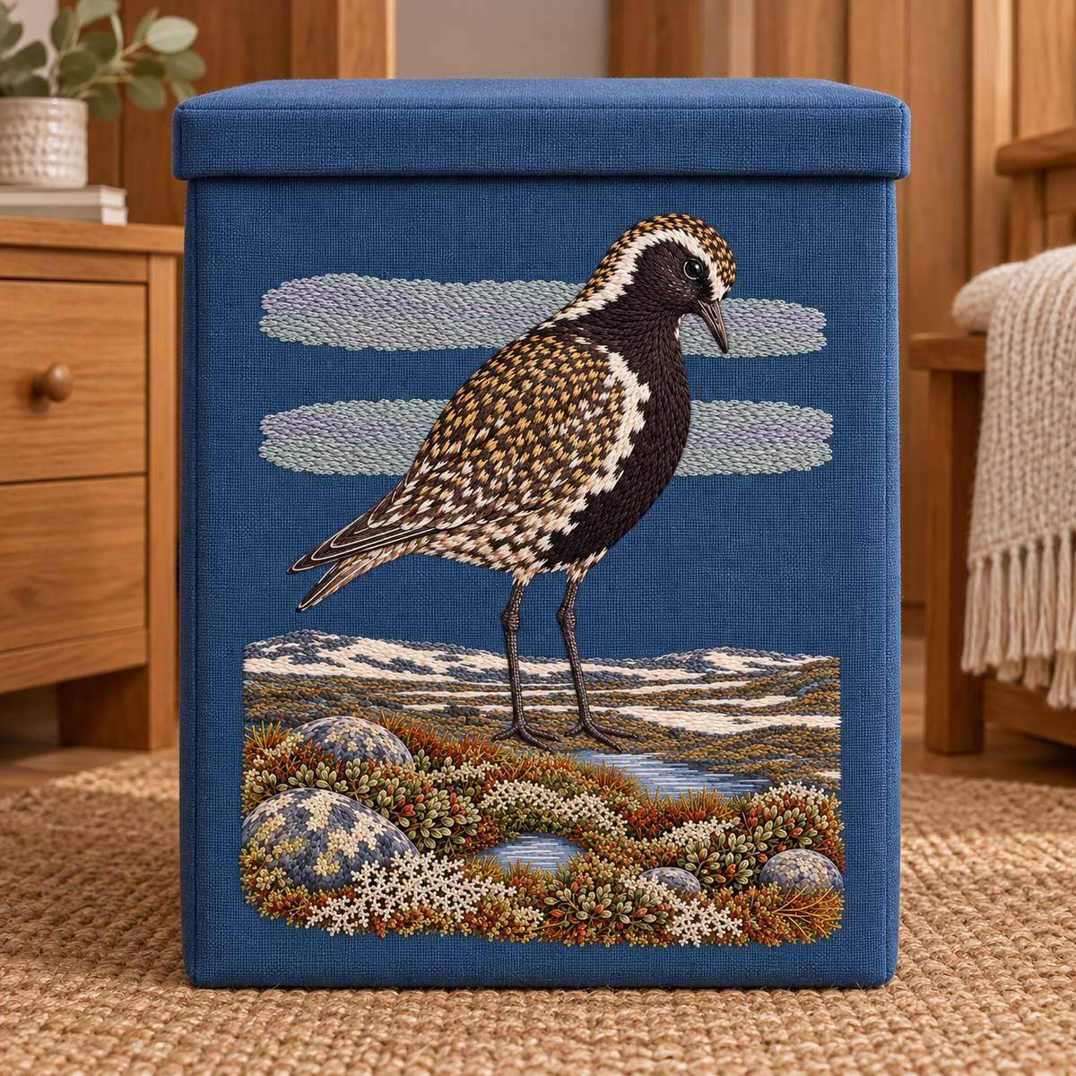 Golden Plover embroidery design in a digital mockup of A tall linen storage hamper with portrait panel on front, lid shut, warm wood dressing room, no cropped ground. Placement inspiration for Study 68.