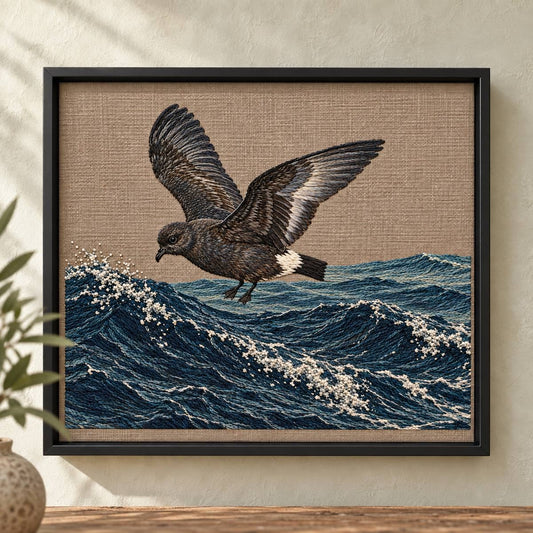 Storm Petrel embroidery design shown in a digital mockup of A landscape embroidery panel in a black metal shadowbox on a pale limewashed wall, narrow visible cloth margins. Study 69.
