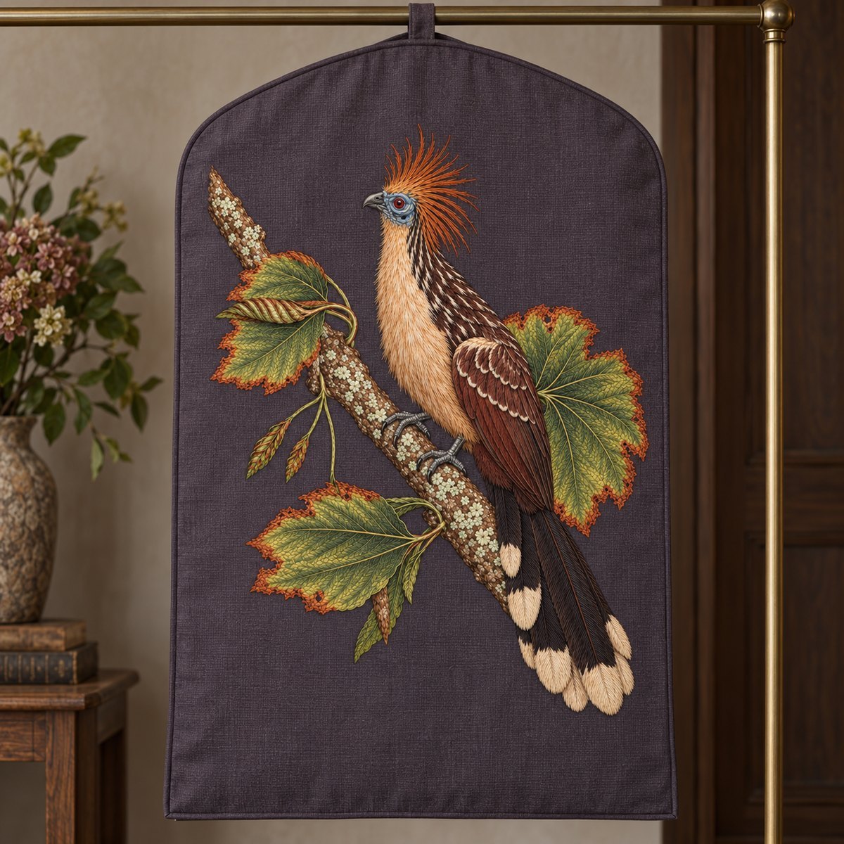 Hoatzin embroidery design in a digital mockup of Aubergine-grey broad linen garment-storage cover hanging flat on a studio rail, entire tall motif on its uninterrupted front, no zipper across art. Placement inspiration for Study 75.