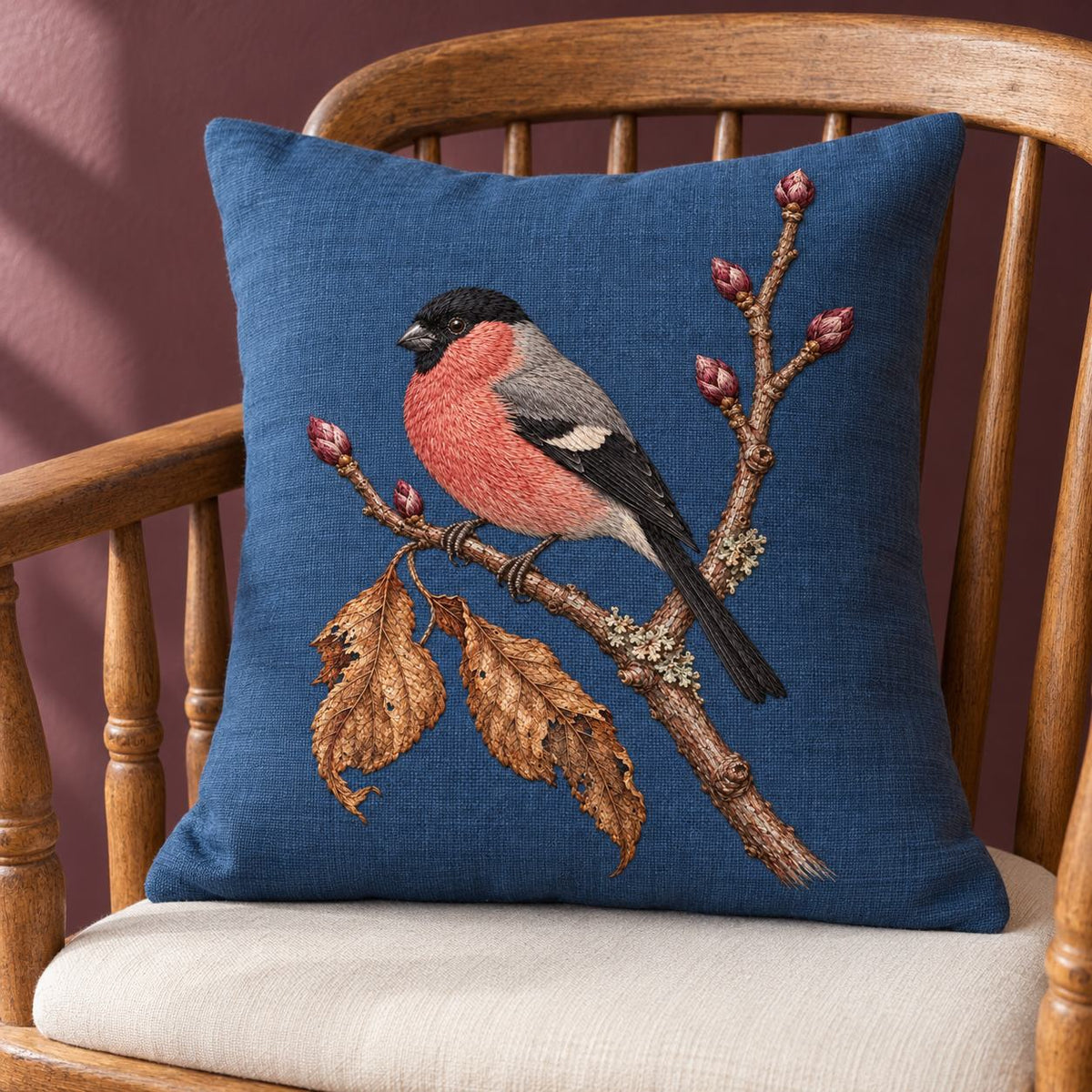 Bullfinch Under the Winter Buds visual mockup shown on a cushion in a lounge chair, with the design on muted blue linen.