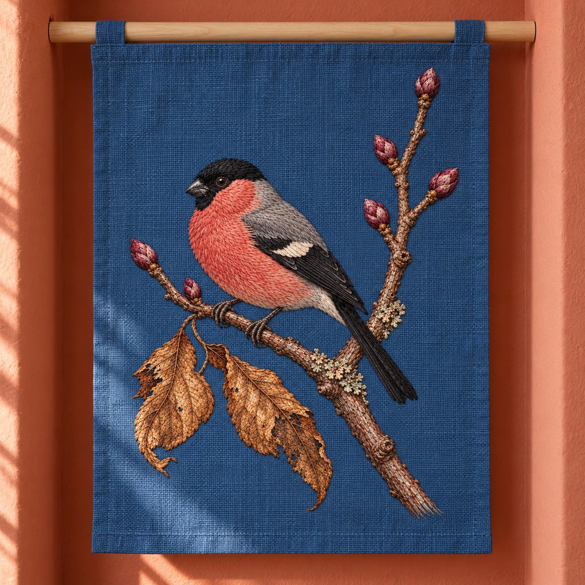 Bullfinch Under the Winter Buds visual mockup shown as a hanging textile held by wooden rails, with the design on muted blue linen.
