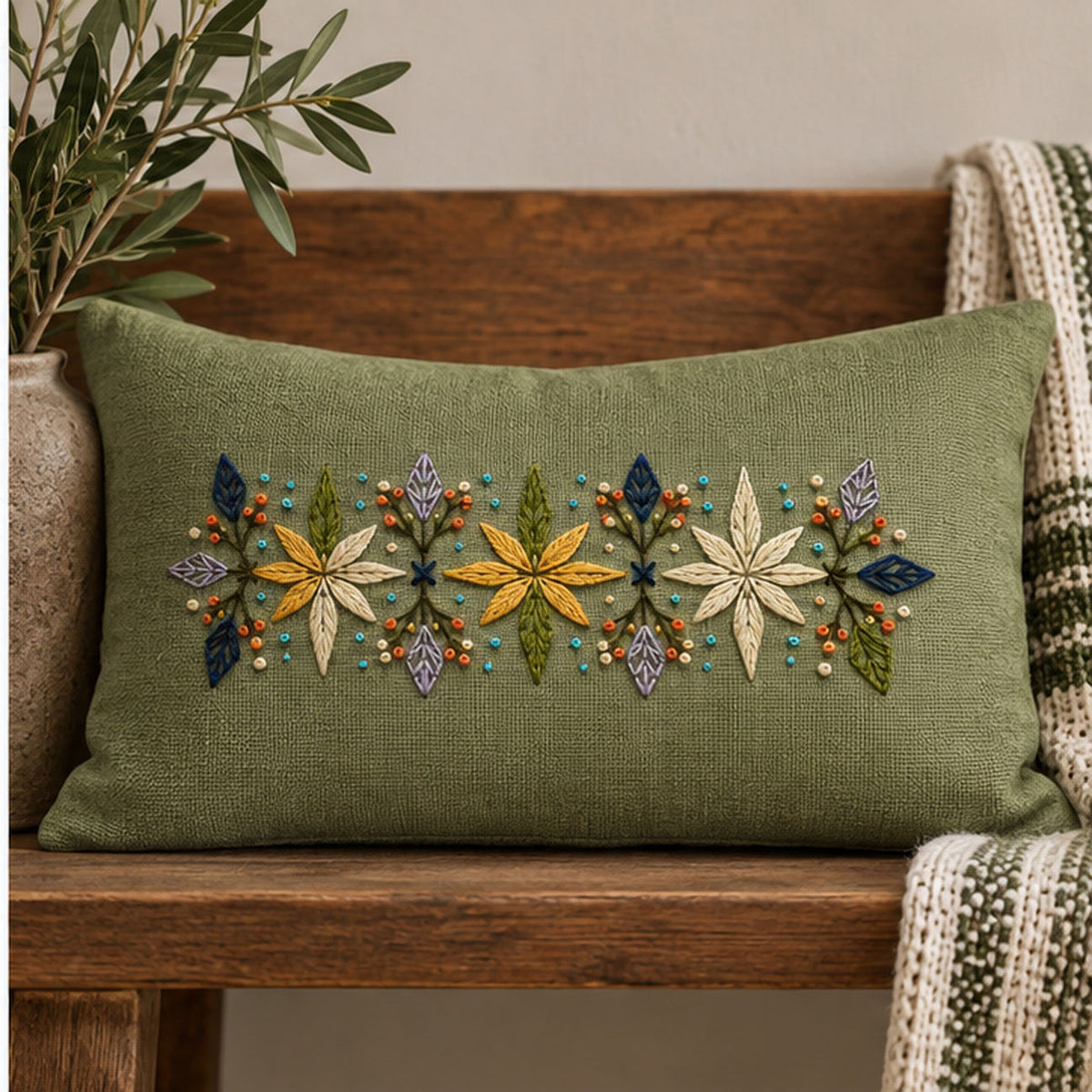 Long green linen cushion mockup featuring the Eight-Point Floral Band hand embroidery design. Eight-point flowers alternate with faceted leaves and small knot accents in this floral embroidery band.