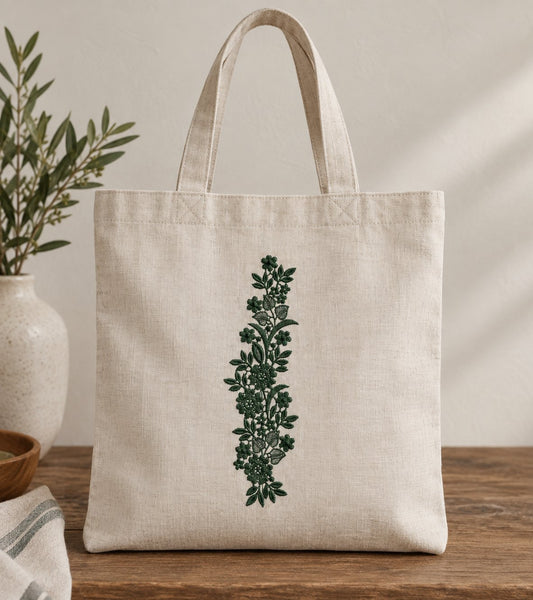 Natural linen tote with a forest green vertical floral vine and open lattice leaf details.