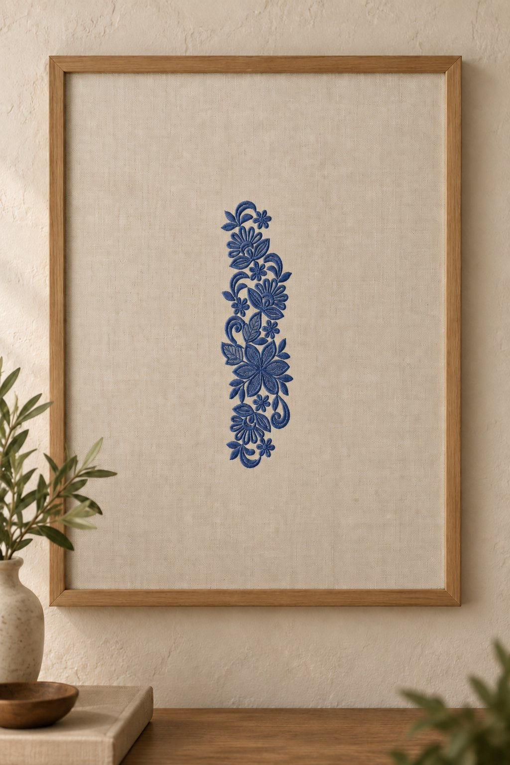 Styled framed linen panel mockup with a single deep smoky indigo blue fan flower botanical spray embroidered on pale linen; the complete motif has clear fabric around it.