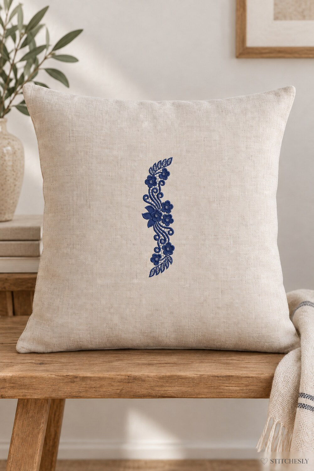 Generated usage mockup of a linen cushion with the leaf capped floral scroll machine embroidery motif in one deep midnight indigo blue thread color.