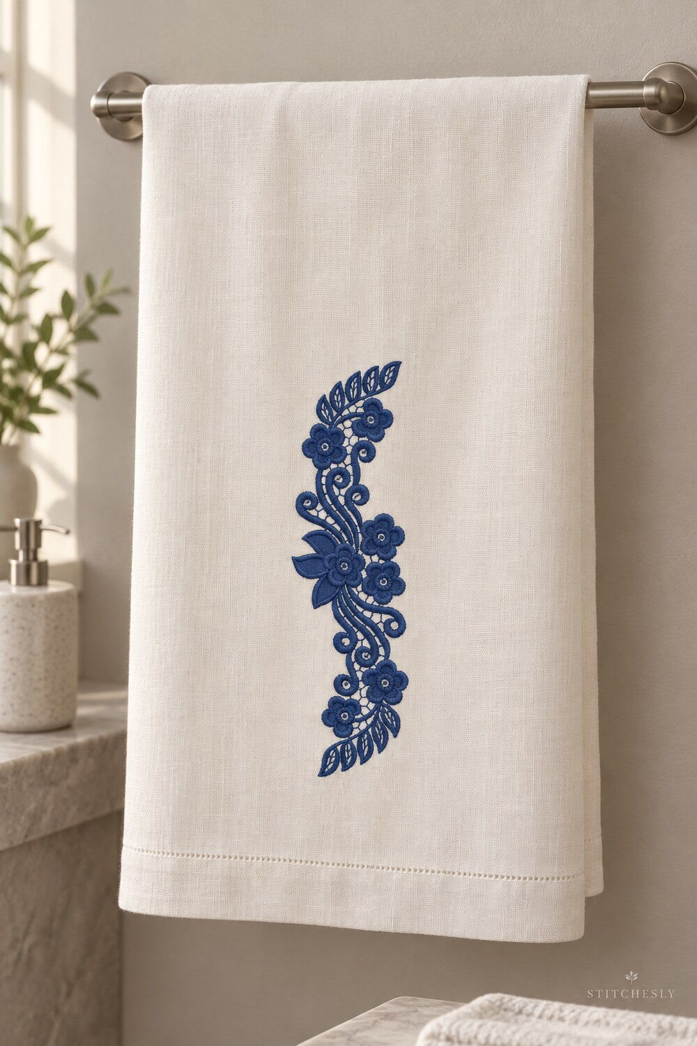 Generated usage mockup of a linen guest towel with the leaf capped floral scroll machine embroidery motif in one deep midnight indigo blue thread color.