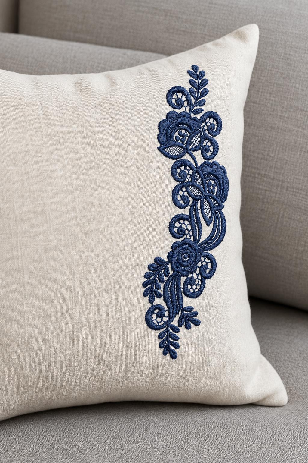 Photorealistic vertical floral lace spray machine embroidery in deep ink blue thread on a linen lumbar cushion, shown as one fabric-stitched motif