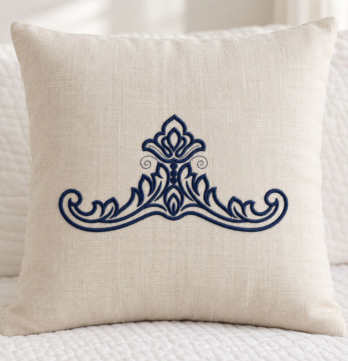 Photorealistic acanthus leaf crest machine embroidery in deep ink navy thread on a natural linen cushion, shown as one fabric-stitched motif