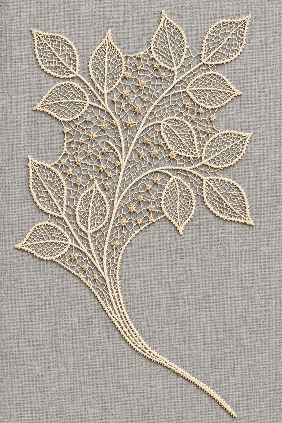 Warm ivory pointed netted leaves and tiny oat seed knots in an irregular needlelace panel on pale stone-grey linen.