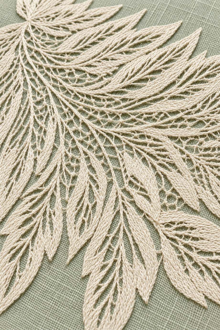 Warm ivory feathery openwork leaf panel with slender pointed leaves and fine mesh on pale celadon linen.
