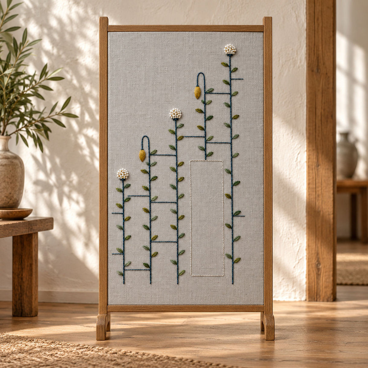 Framed botanical textile mockup featuring the Ladder Stem Meadow hand embroidery design. Meadow stems pass through interrupted ladder bars in this geometric hand embroidery pattern.