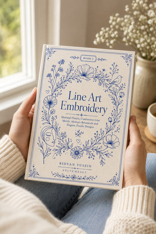 Reader holding the Line Art Embroidery Edition Three book beside a window.
