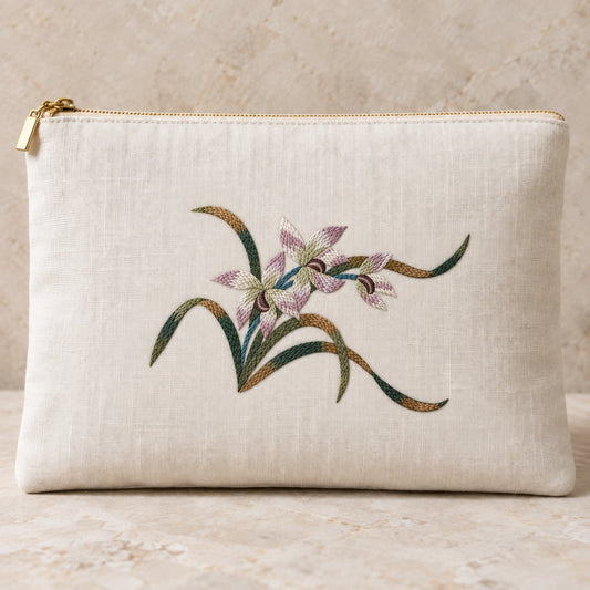 Ivory linen zip clutch embroidered with three mauve and parchment orchids, layered green leaves and dark flower centers.