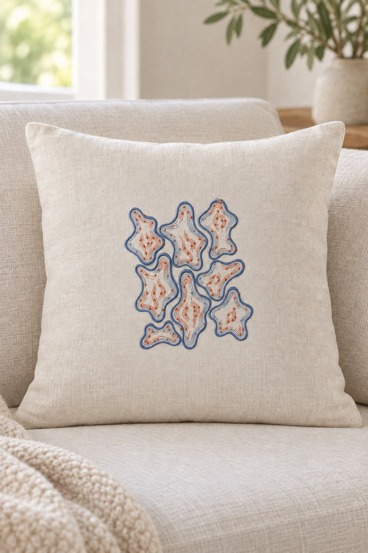 Organic Contour Dot Composition embroidered in smoky indigo and warm terracotta on a linen cushion, showing the complete two-color motif.