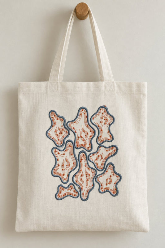 Organic Contour Dot Composition embroidered in smoky indigo and warm terracotta on a linen tote bag, showing the complete two-color motif.