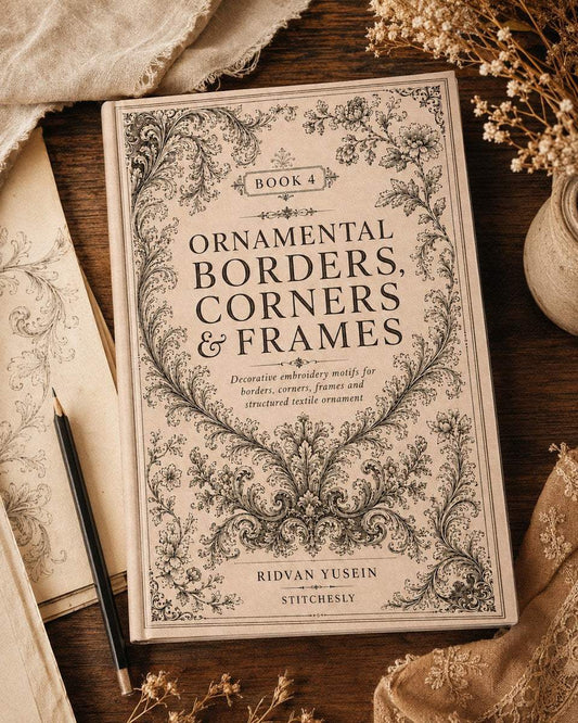 Ornamental Borders, Corners and Frames, Edition Four cover on natural linen beside dried flowers.