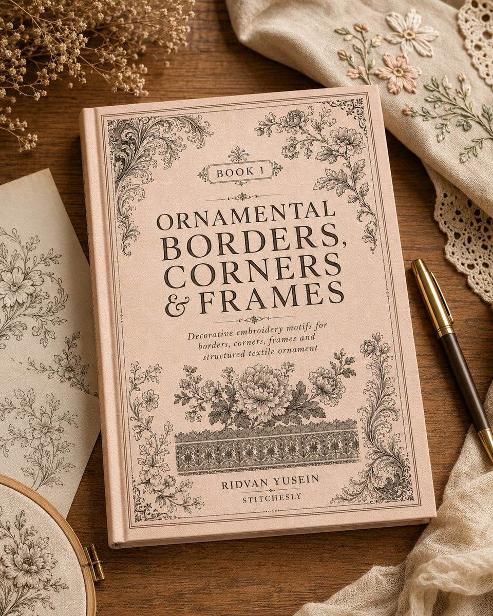Ornamental Borders, Corners and Frames, Edition One cover beside a pencil and linen on a wooden desk.