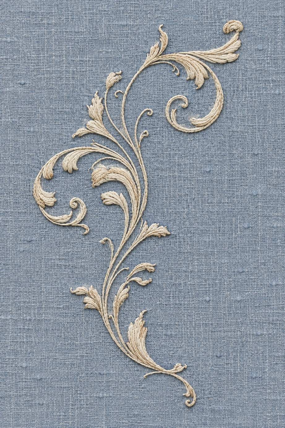 Fine warm ivory cotton airy acanthus scroll spray with slender stems embroidered on dusty blue linen.