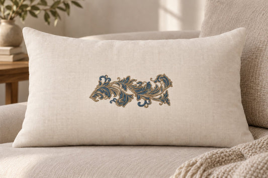 Ivory lumbar cushion featuring one petrol blue and champagne embroidered acanthus scroll in the center.