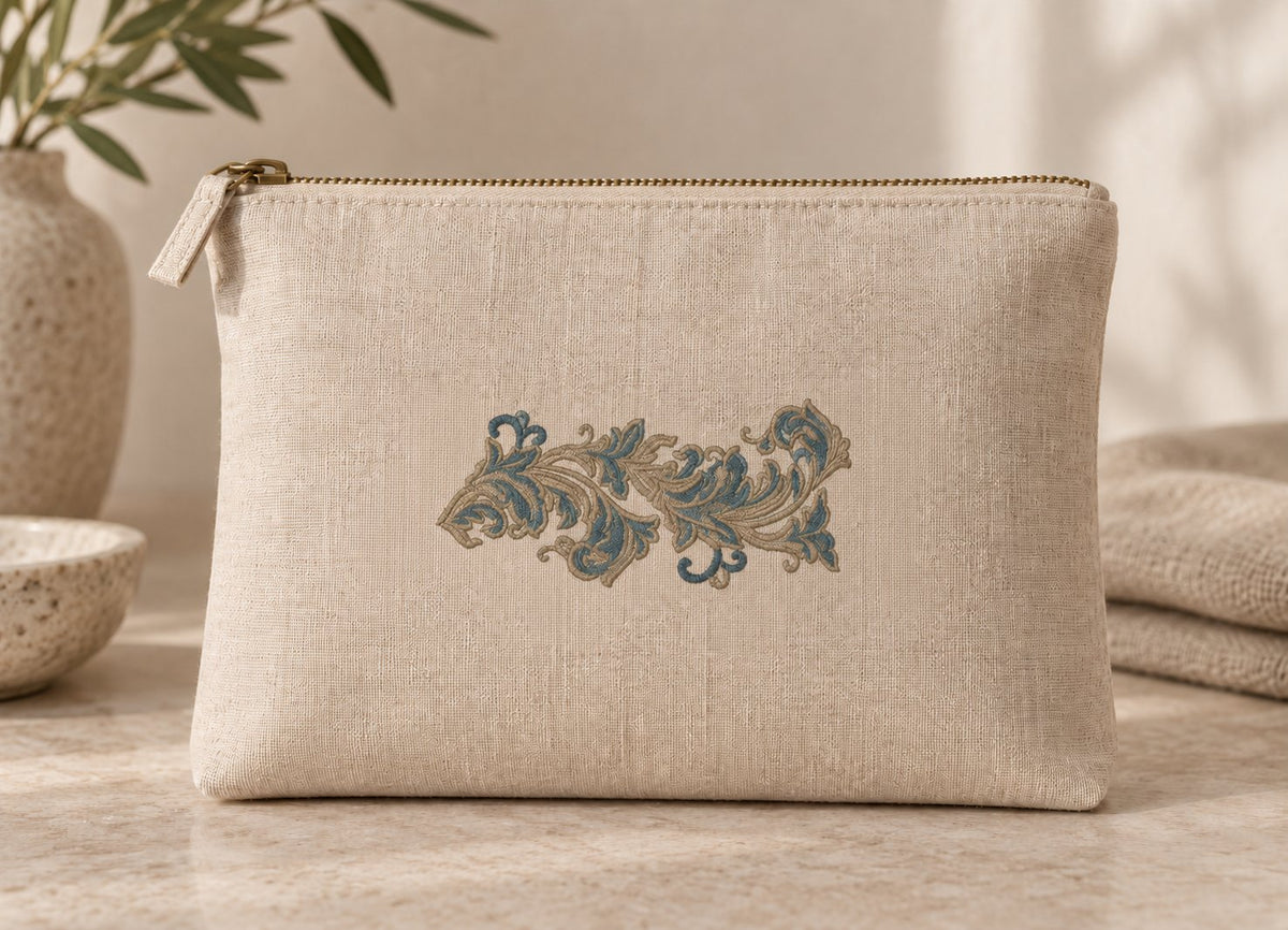 Natural linen zipper pouch with a small two-tone acanthus leaf scroll on its front.