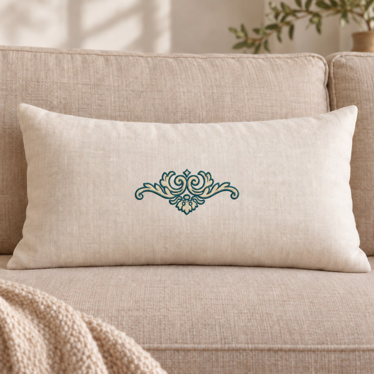 Neutral linen lumbar cushion with a compact petrol-outlined and parchment-filled scroll ornament at its center.