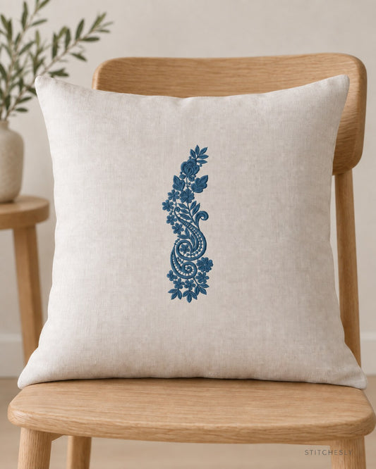 Generated usage mockup of a linen cushion with the rose and twin paisley spray machine embroidery motif in one deep muted petrol blue thread color.