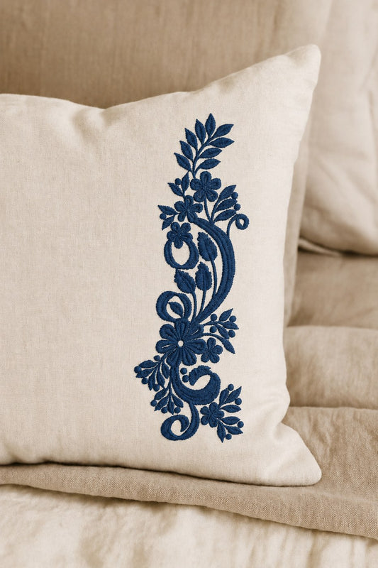 Tall floral paisley machine embroidery stitched in deep Prussian blue on a warm ivory linen cushion