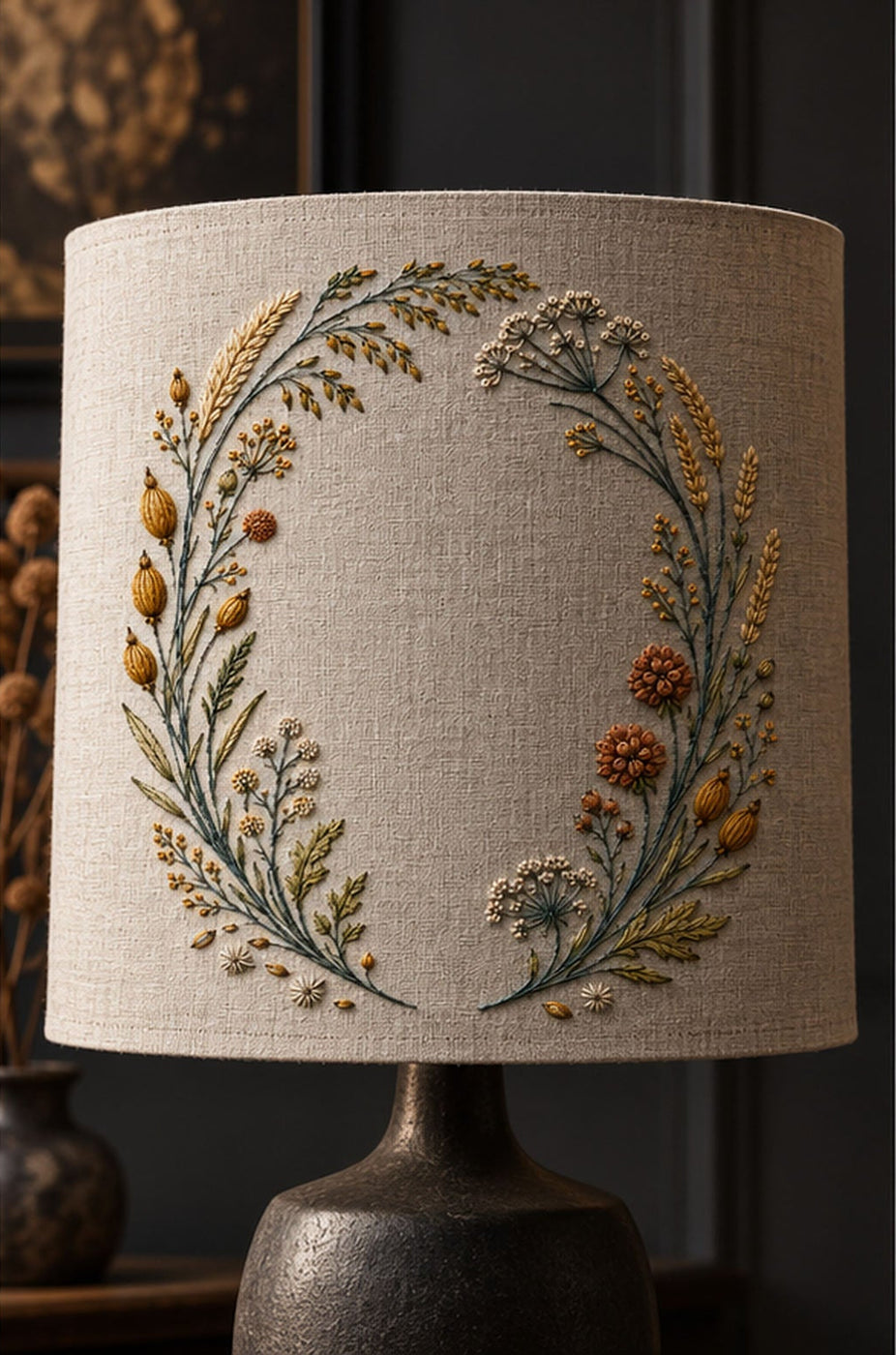 Round linen cushion mockup featuring the Seedhead Circle with Open Gate hand embroidery design. Pods, spikelets, umbels and grasses follow a circle with a lower-centre opening.