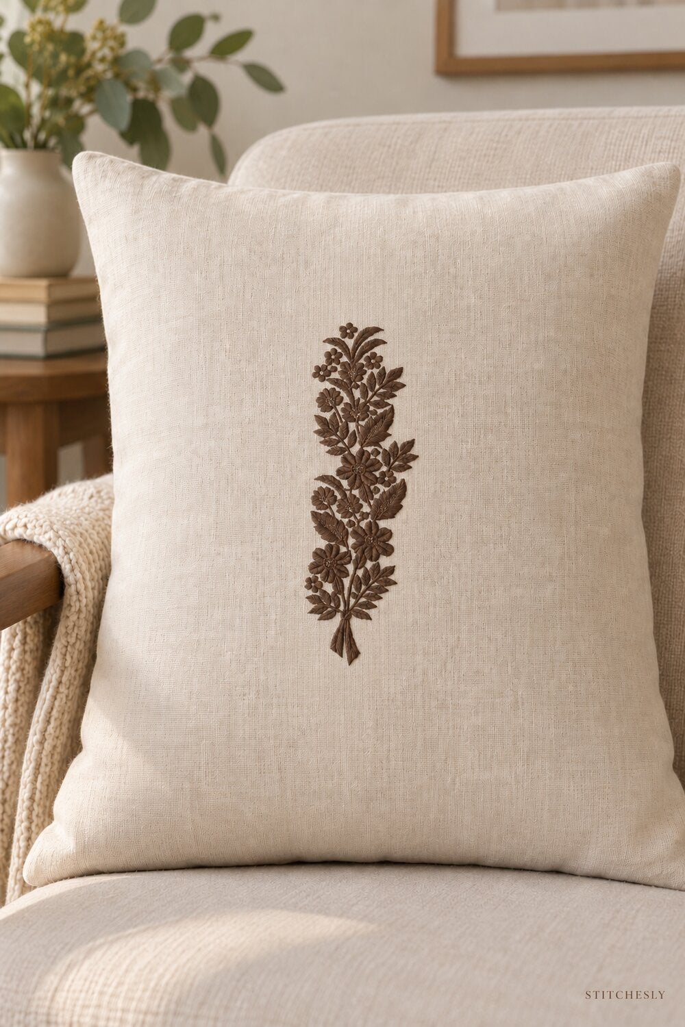 Generated usage mockup of a linen cushion with the ribbon tied meadow bouquet machine embroidery motif in one rich muted dark sepia brown thread color.