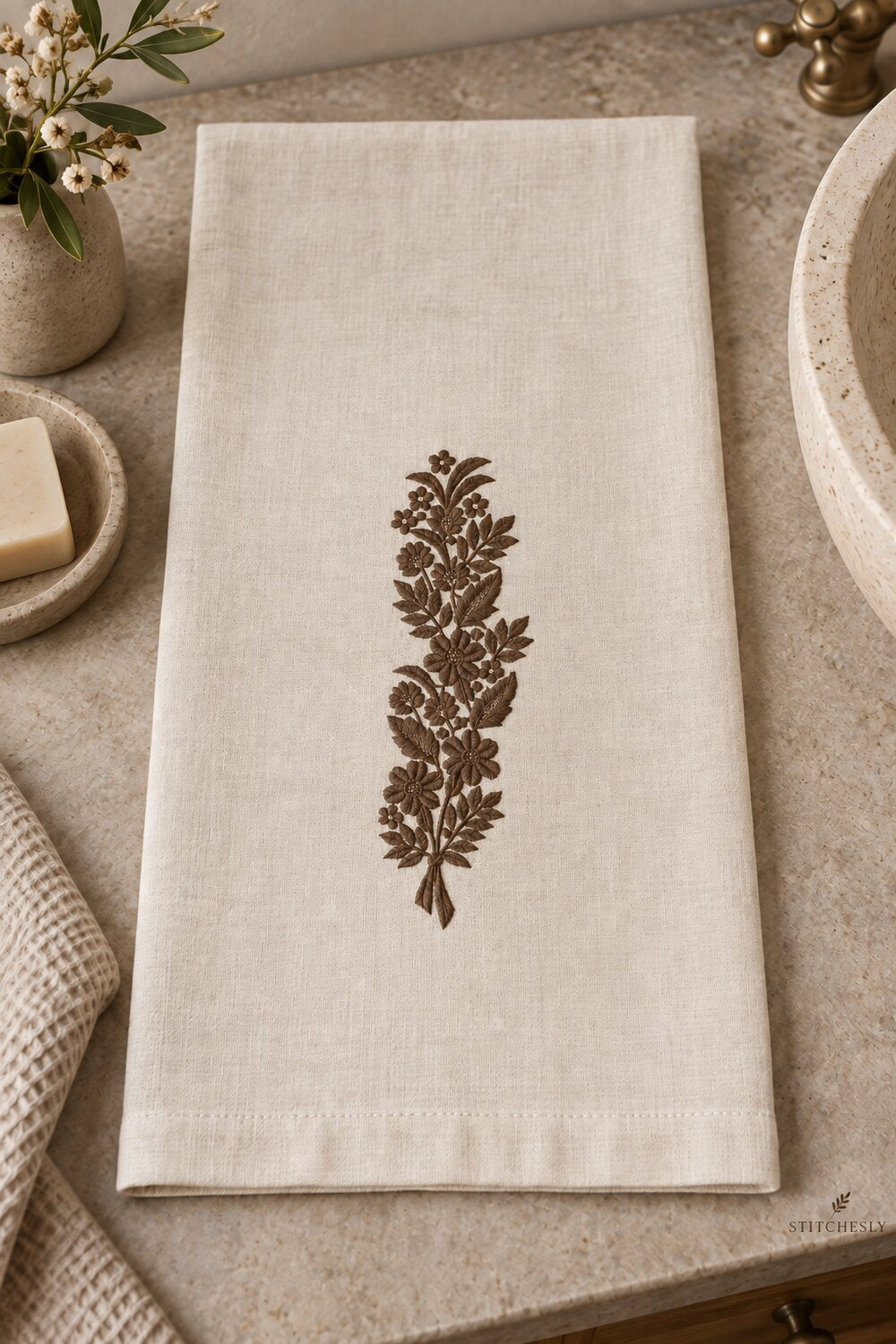 Generated usage mockup of a linen hand towel with the ribbon tied meadow bouquet machine embroidery motif in one rich muted dark sepia brown thread color.