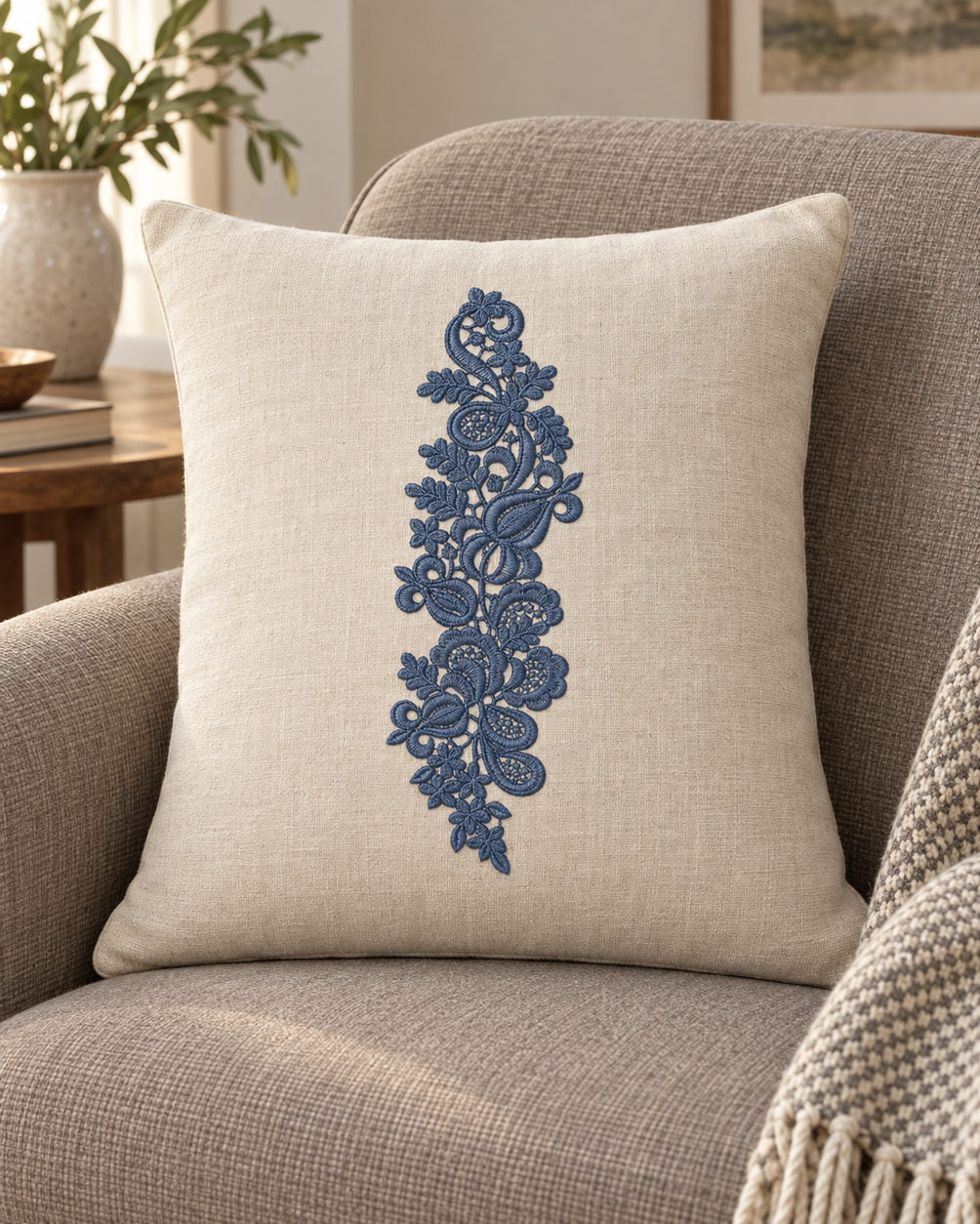 Linen cushion with a single deep slate blue machine-embroidered paisley lace botanical spray motif on natural ivory linen.