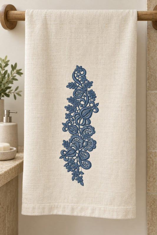 Linen guest towel with a single deep slate blue machine-embroidered paisley lace botanical spray motif on natural ivory linen.