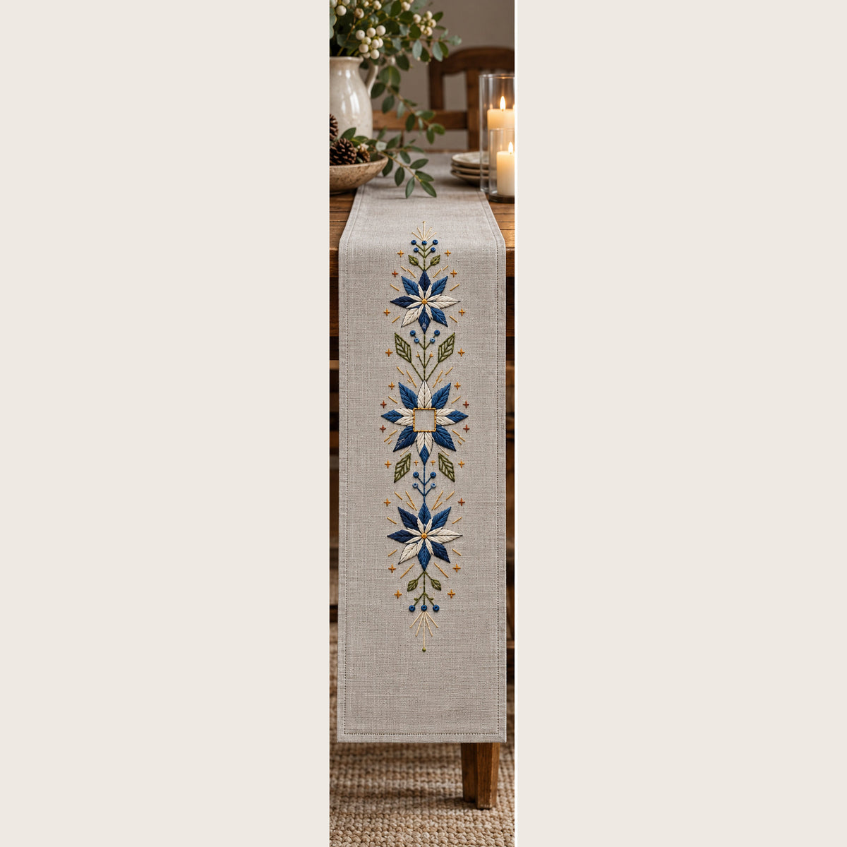 Long linen table runner mockup featuring the Snowflower Center Panel hand embroidery design. Blue-white snowflowers form a narrow vertical arrangement around an unfilled square detail.