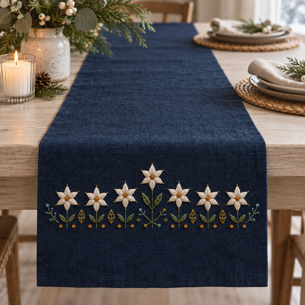 Navy linen apron mockup featuring the Starflower Border Chain hand embroidery design. White starflowers form a low border on indigo, with a taller central bloom and small geometric ground marks.