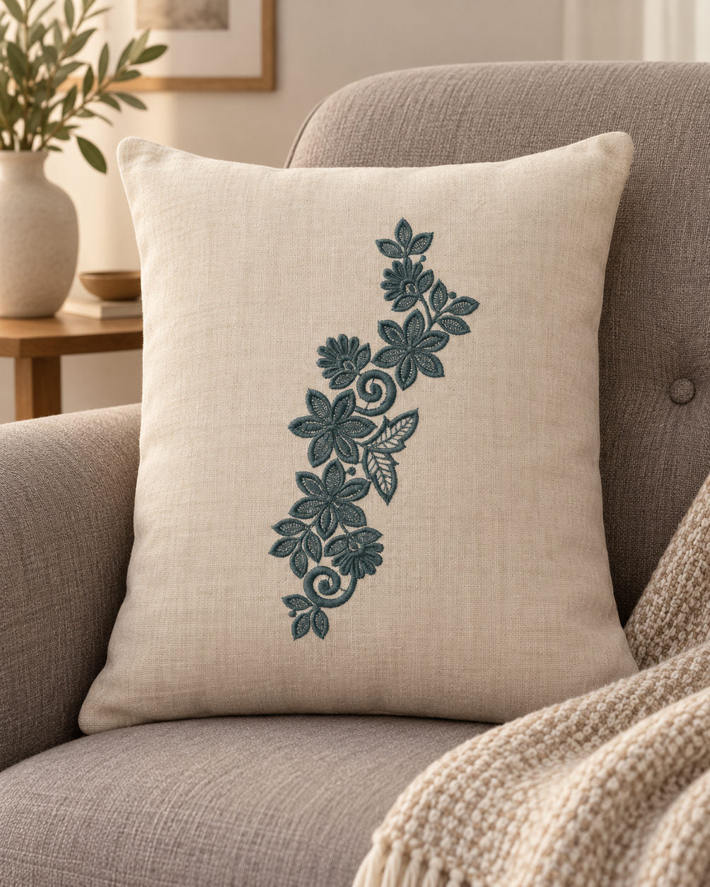 Linen cushion with a single deep muted teal green machine-embroidered star bloom and fan flower vine motif on natural ivory linen.