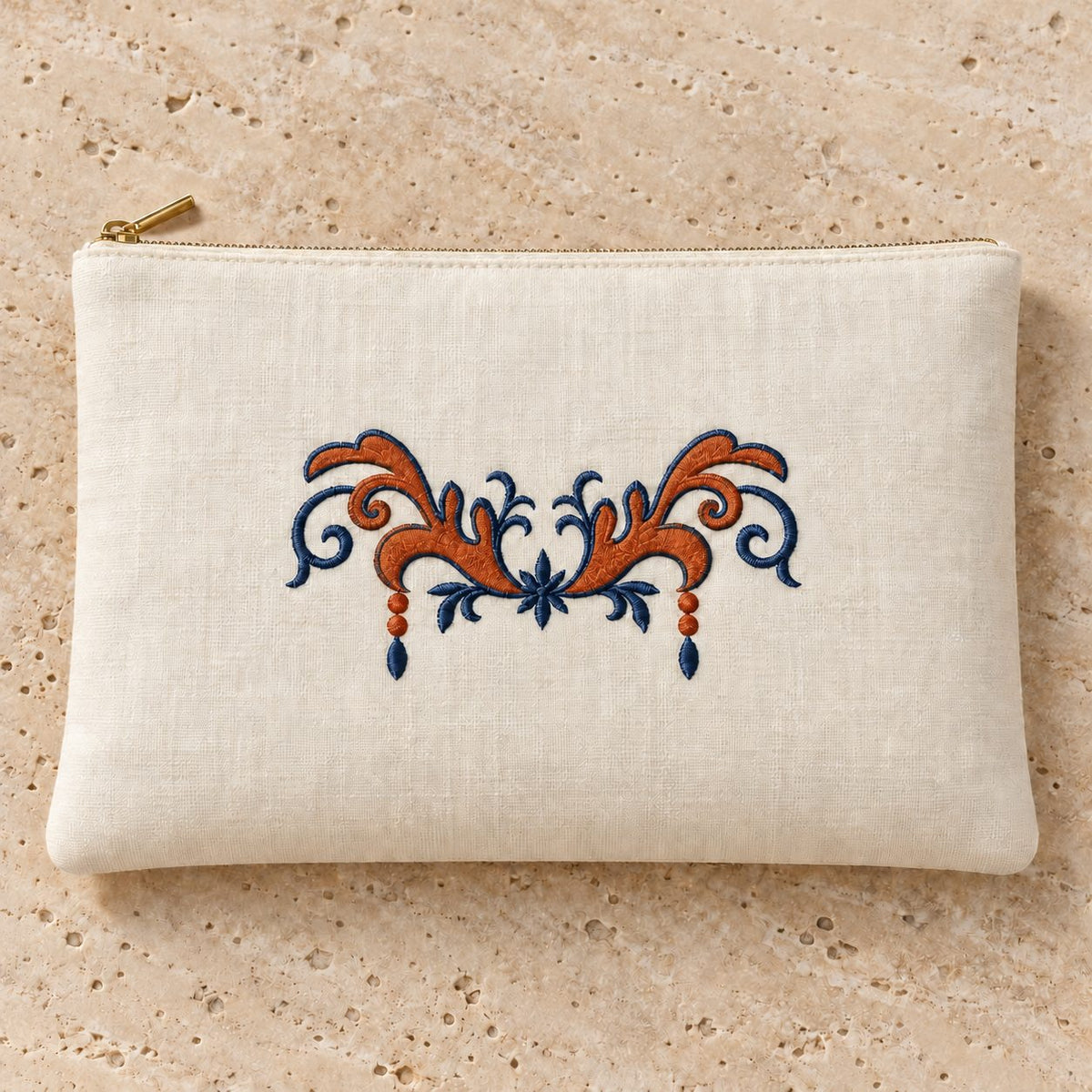 Ivory linen zip clutch with terracotta acanthus leaves, midnight-blue outlines and twin embroidered drops.