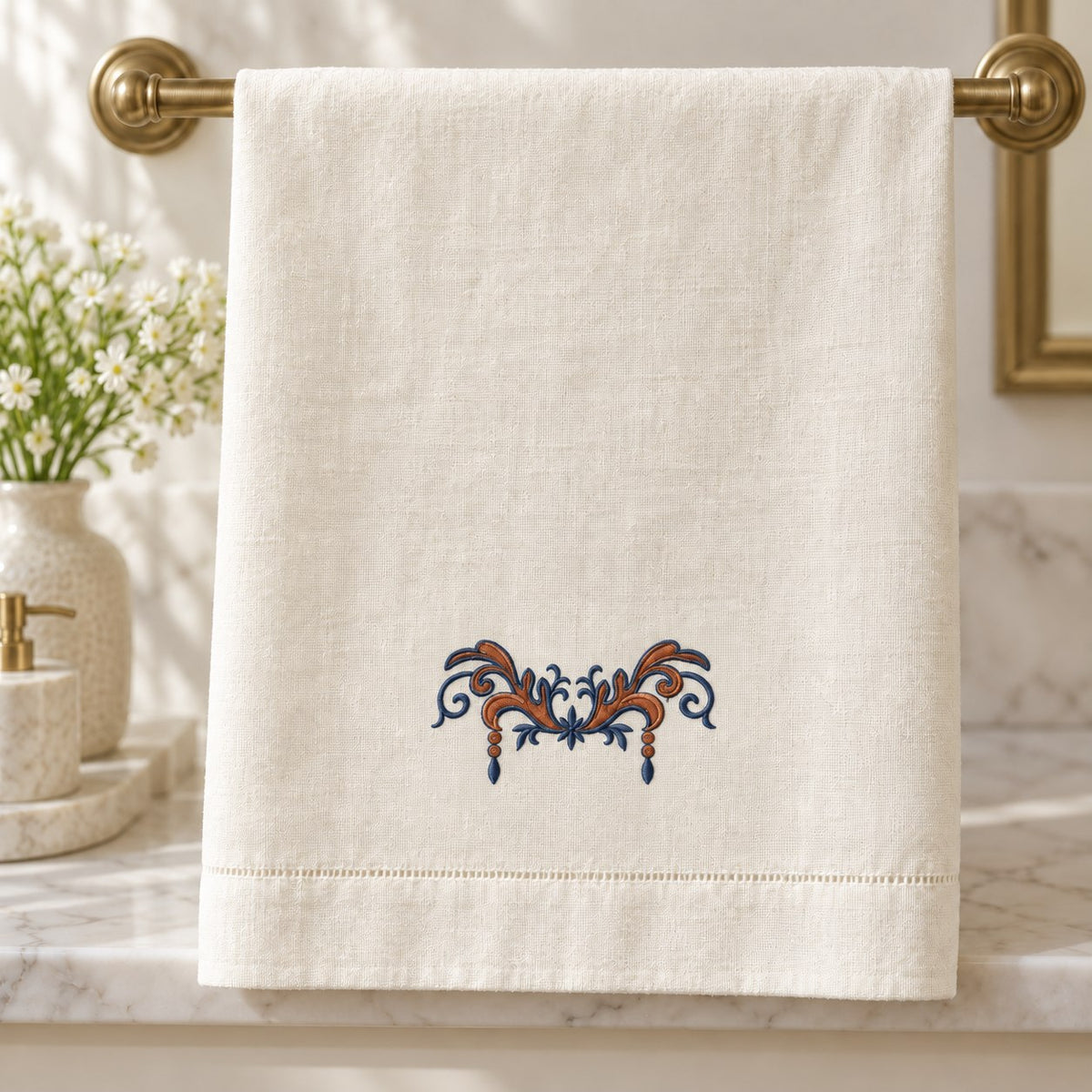Linen hand towel with a compact two-color acanthus swag above the hem, hanging from a brass rail.