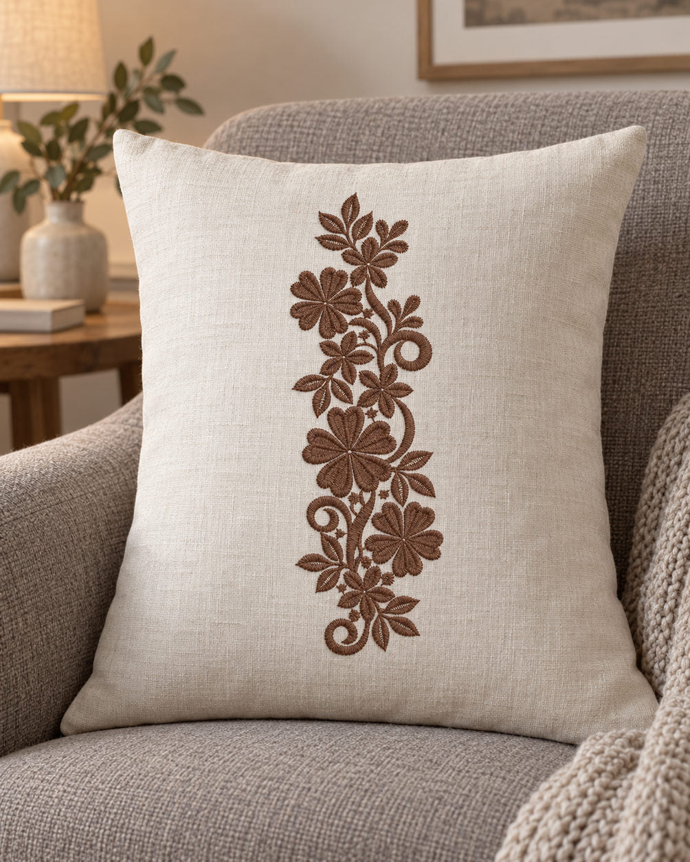 Linen cushion with a single rich muted walnut brown machine-embroidered heart petal floral scroll motif on natural ivory linen.