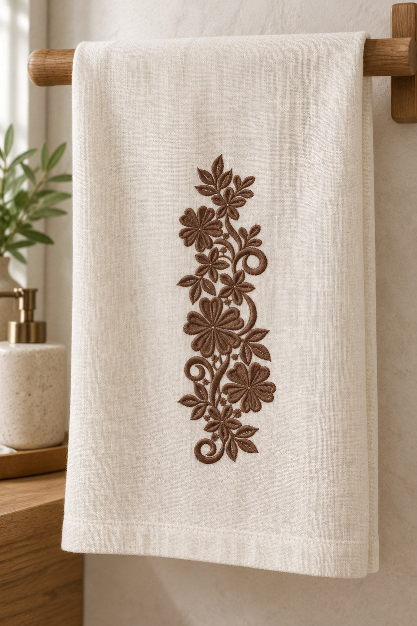 Linen guest towel with a single rich muted walnut brown machine-embroidered heart petal floral scroll motif on natural ivory linen.