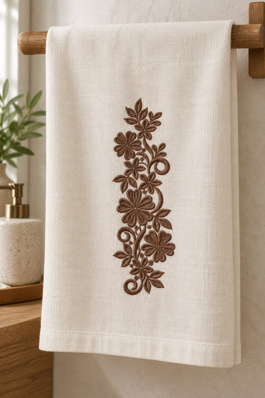 Linen guest towel with a single rich muted walnut brown machine-embroidered heart petal floral scroll motif on natural ivory linen.