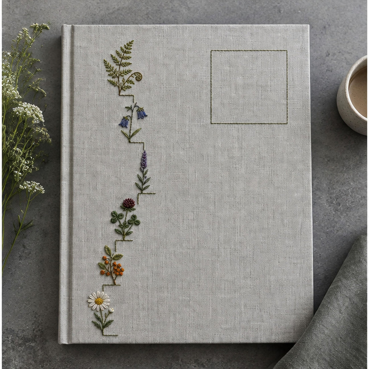 Botanical textile flat lay mockup featuring the Wildflower Stair Border hand embroidery design. Wildflowers climb a stepped left border beside an outlined area of clear linen.